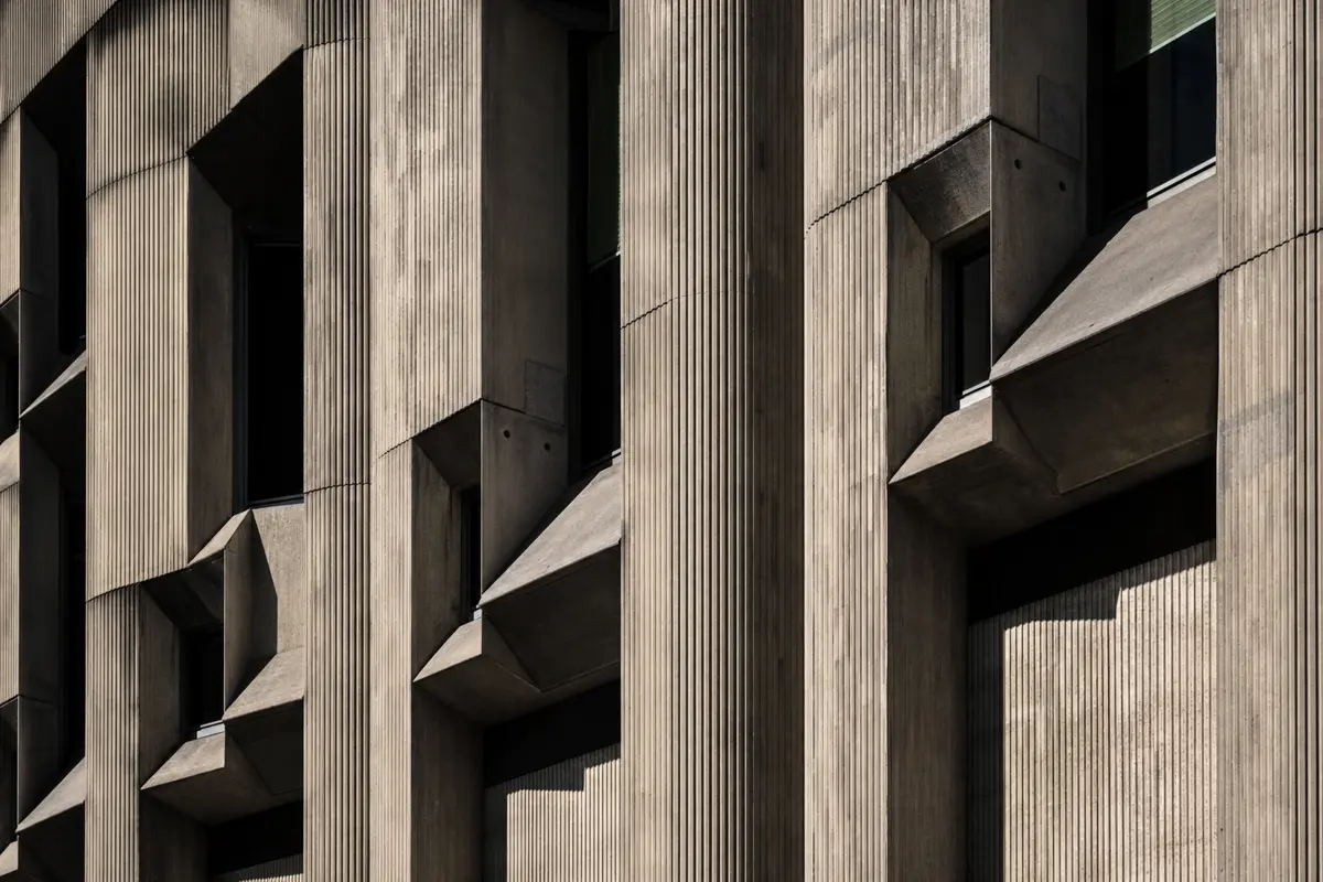 Side-lit brutalist concrete facade with strong texture